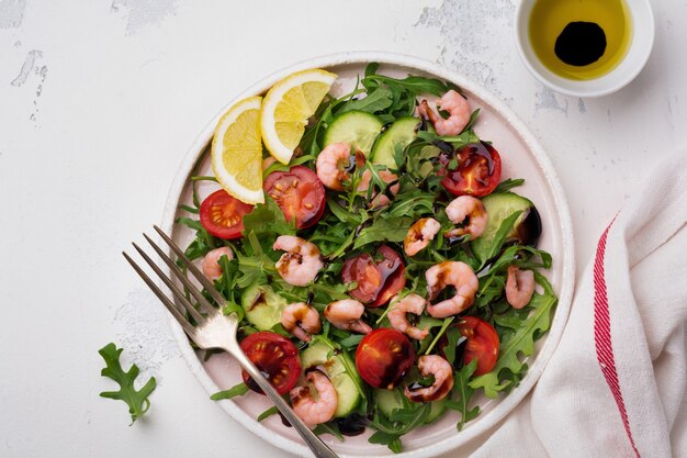 Arugula, 오이, 토마토 및 새우 샐러드와 세라믹 접시에 간장. 선택적 초점. 평면도.