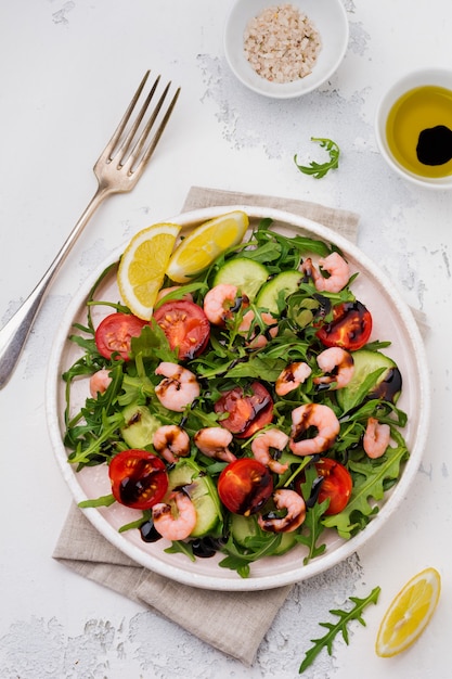 Arugula, cucumber, tomato and shrimp salad with soy sauce on a ceramic plate