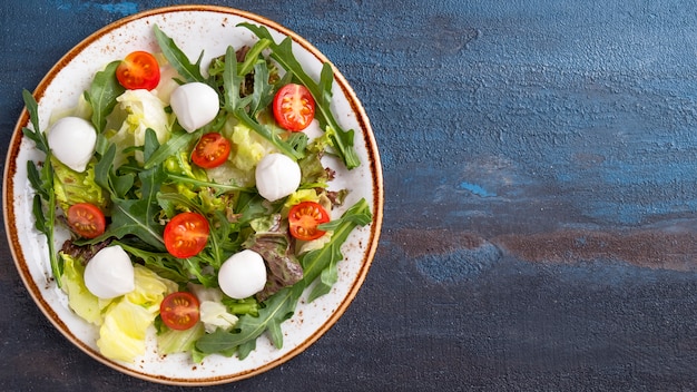 Arugula, lettuce, cherry tomatoes and mozzarella cheese on a plate