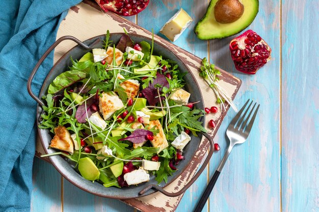 Arugula salad with chicken avocado pomegranate and cheese on wooden table Top view Copy space