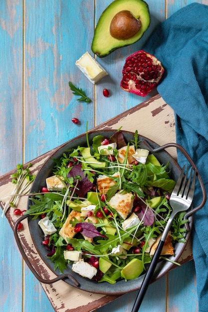 Arugula salad with chicken avocado pomegranate and cheese on wooden table Top view Copy space