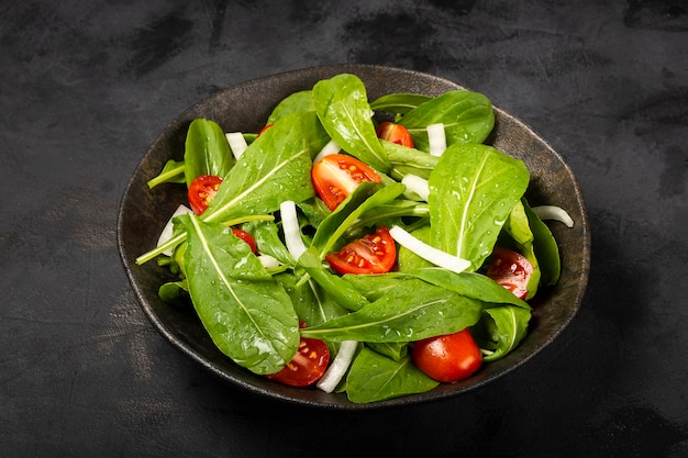 어두운 배경에 토마토를 곁들인 Arugula 샐러드