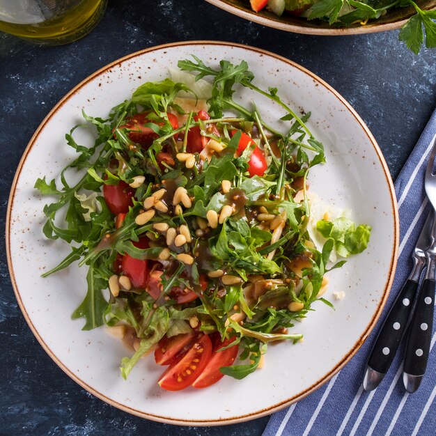 Arugula with pine nuts, tomatoes and cheese. Healthy fresh salad with arugula. Top view.