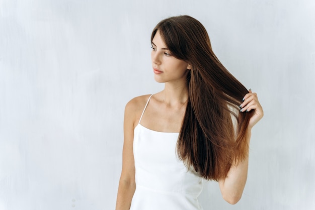 Свободен, как ветер. Портрет очаровательной милой женщины стоит и смотрит в сторону, наслаждаясь качеством своих длинных волос. Изолированный фон