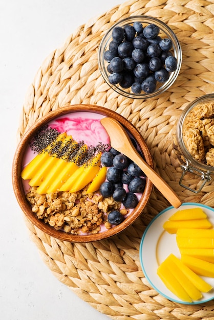 Asai bowl granola oatmeal with mango blueberry and chia seeds in wooden plate on white background copy space top view