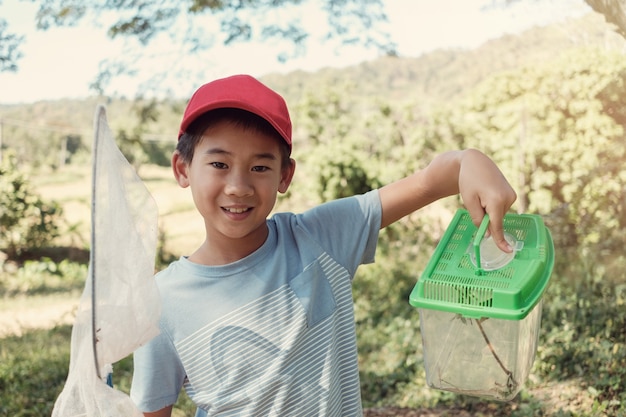 Asain jongen botterfa&#39;s vangen met een net en een doos met insecten vasthouden