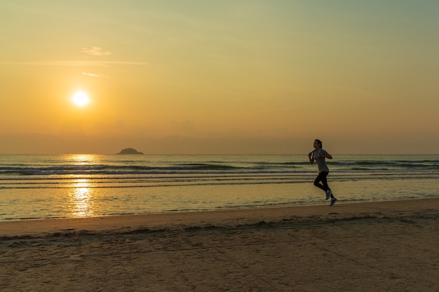 朝日が昇るビーチを走る朝日女。現代人の健康とヘルスケアのコンセプト。