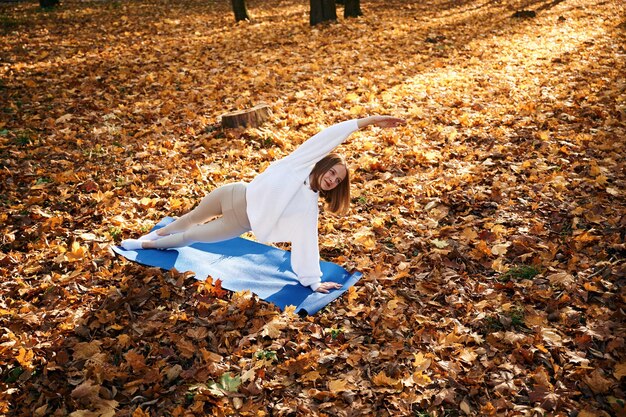 Asana for flexibility Young beautiful woman is doing yoga in the autumn park