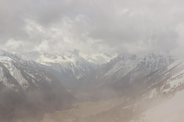 Ascent to pastukhova mountain on arkhyz snowcapped mountains with low clouds