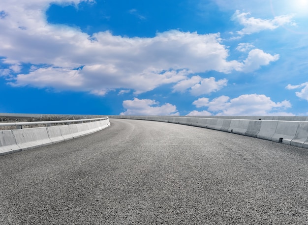 Asfaltverhardingen en vierkante vloertegels onder de blauwe lucht en witte wolken