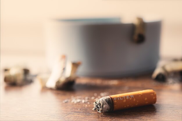 Ashtray with cigarette on wood table.