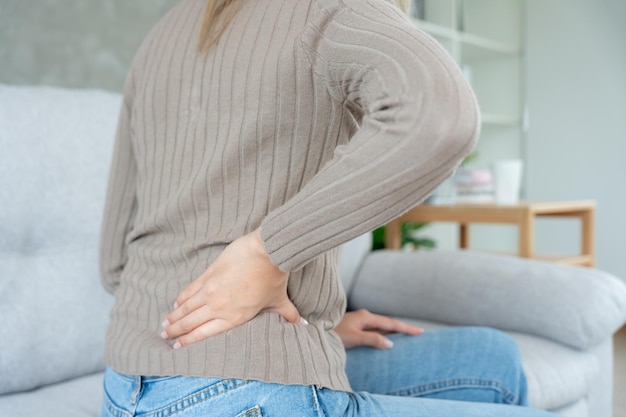 Asia beautiful woman holding her lower back while and suffer from unbearable pain health and problems chronic back pain backache in office syndrome scoliosis herniated disc muscle inflammation