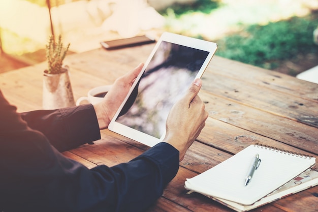 Photo asia business man holding tablet on table in coffee shop with vintage toned filter.