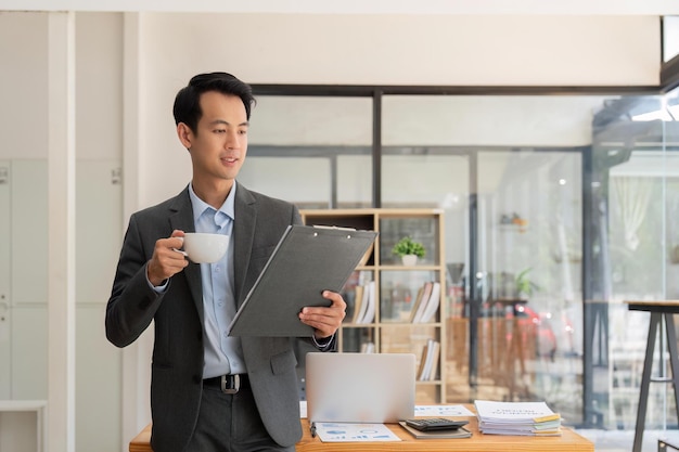 Asia businessman at office and paperwork and holding cup of coffee