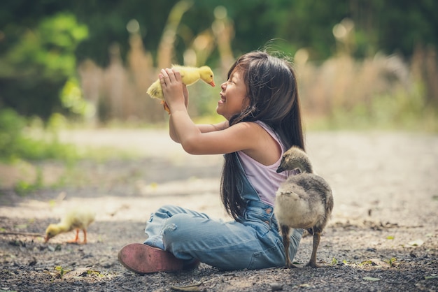 Asia children girl holds a duck in hands