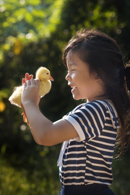 Asia children girl holds a duck in hands.