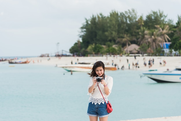 アジアの女の子がビーチで写真を撮る