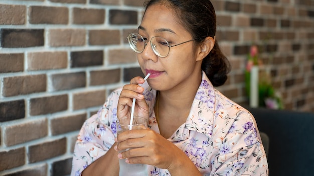 Asia holding A Glass of water and Drinking in the shop on wall back ground