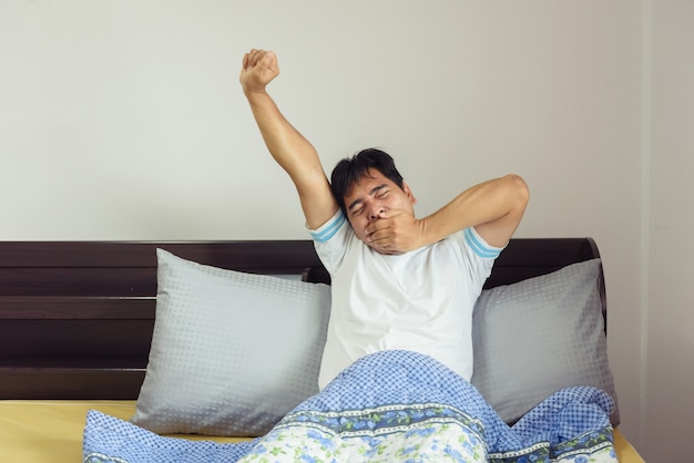  Asia man stretching in bed after wake up