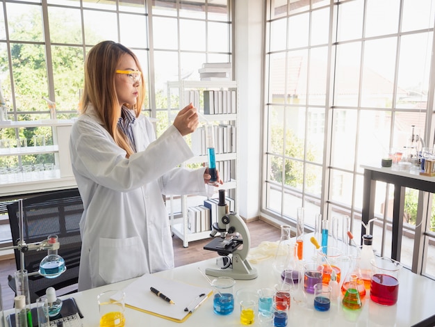 Asia scientific researcher holding a test tube of clear solution in a lab