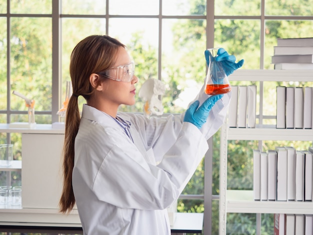 Asia scientific researcher holding a test tube of clear solution in a lab