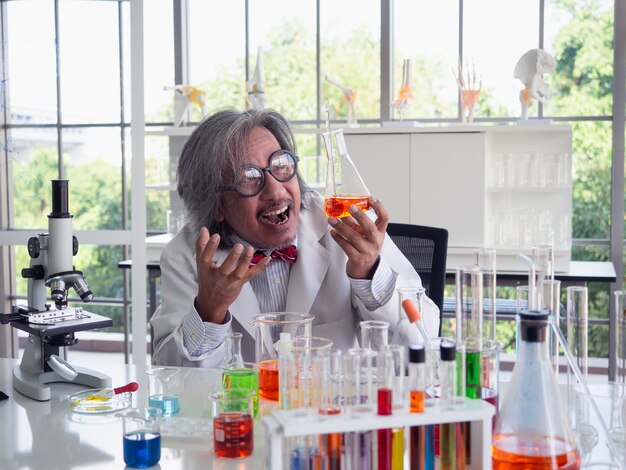Asia scientific researcher holding a test tube of clear solution in a lab