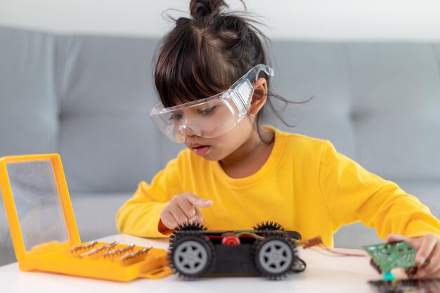 Asia students learn at home in coding robot cars and electronic board cables in STEM, STEAM, mathematics engineering science technology computer code in robotics for kids concept.