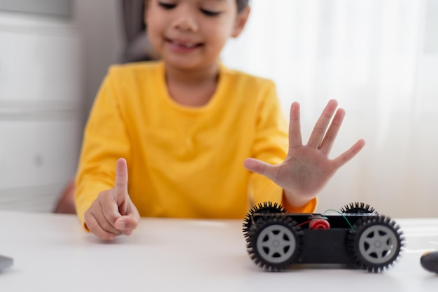 Gli studenti asiatici imparano a casa nella codifica di auto robot e cavi per schede elettroniche nel codice del computer stem steam matematica ingegneria scienza tecnologia nel concetto di robotica per bambini