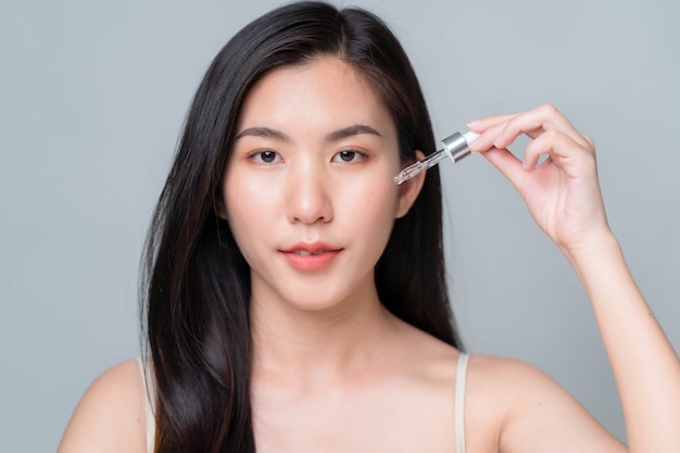 Asia woman applying hyaluronic serum on her face with pipette