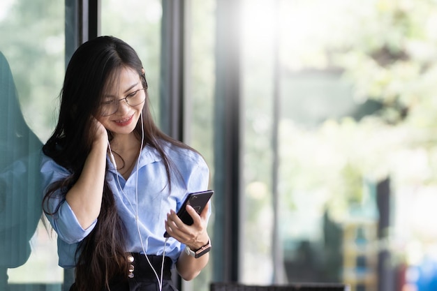 写真 アジアの女性はインターネットカフェでパソコンとスマートフォンに取り組んでいます