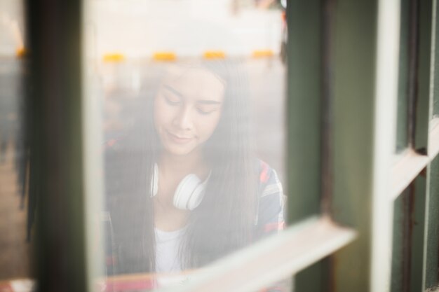 Donna dell'asia che ascolta la musica con felice dentro la caffetteria.