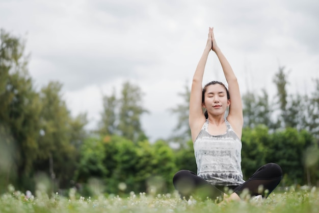 Asia woman practices yoga and meditates at park. Healthy lifestyle and Yoga concept.