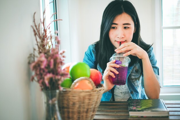 책을 읽고 커피 숍에서 주스를 마시는 아시아 여자.