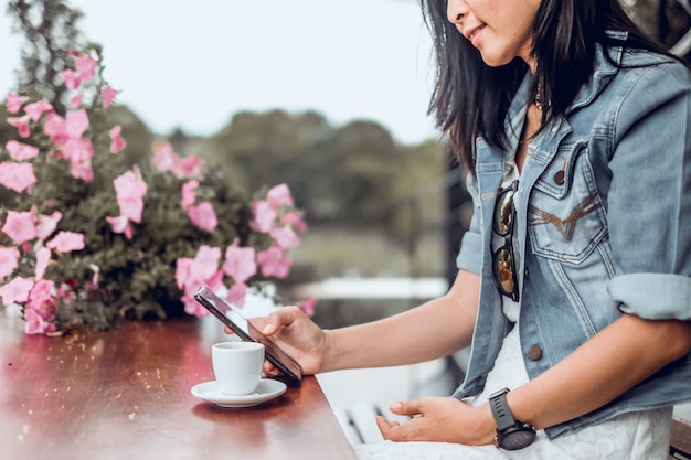 アジアの女性がコーヒーショップに座っていると携帯電話を使用して