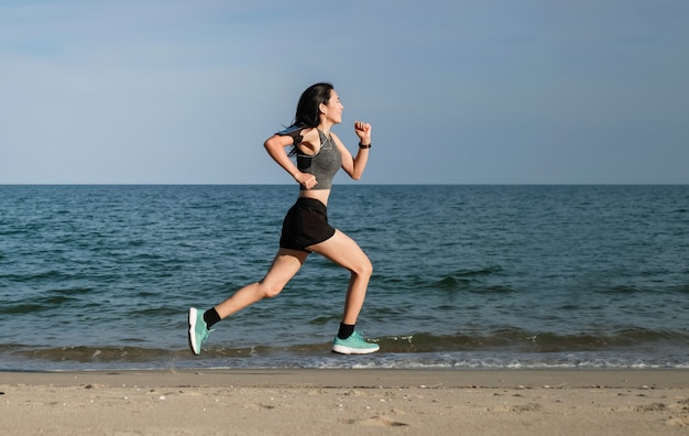 Asia woman in sport ware exercising and running on the beach.