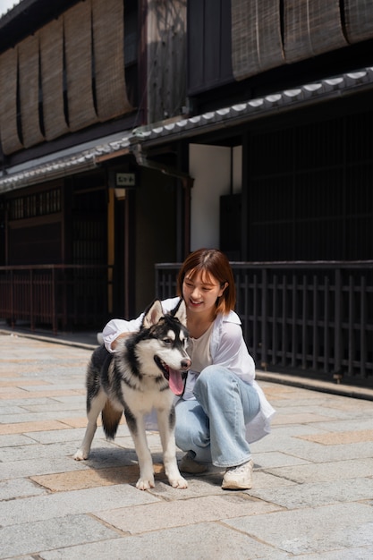 写真 屋外でハスキー犬を散歩するアジアの女性