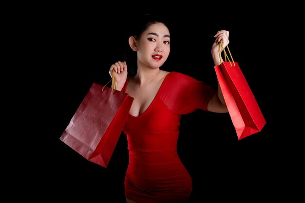 Asia woman wearing a red dress holding credit card and shopping bags