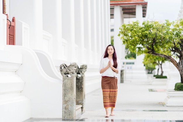 タイの伝統的な衣装を着て瞑想を歩き、教会で祈るアジアの女性