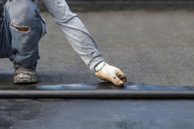 asia worker installing tar foil on the rooftop of building. 