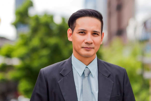 Asia young business man in front of the modern building in downtown .