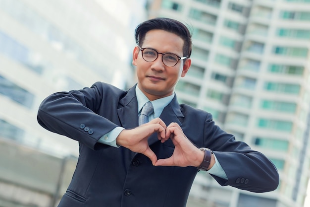 Asia young businessman making a heart with his hands over white background, I love business