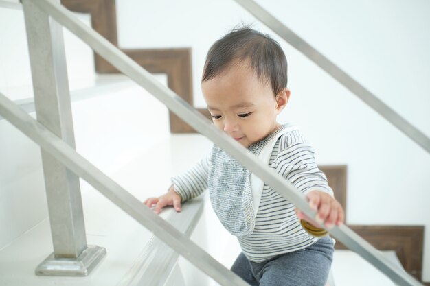 Asian 10 months old toddler baby girl child climbing up stairs at home alone, Movement, Stair climbing developmental milestone concept