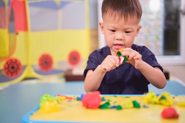 アジア2〜3歳の幼児の男の子の子供がカラフルなモデリング粘土で遊ぶ/家で生地をする、子供の教育用おもちゃ