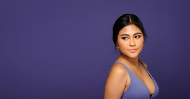 아시아 20대 여성 통통한 스포츠 브래지어는 보라색 배경 위에 있거나 베리 페리 세계 트렌드 반신반신 여성 흑발은 스튜디오 조명에서 얼굴 눈에 강한 미소를 표현합니다.