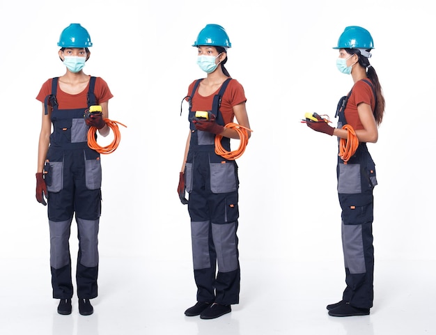 Asian 20s woman wear blue uniform orange shirt hardhat and glove as electric fix repair guy with cable. Full length of tall female stand hold multi voltage meter many poses, white background isolated