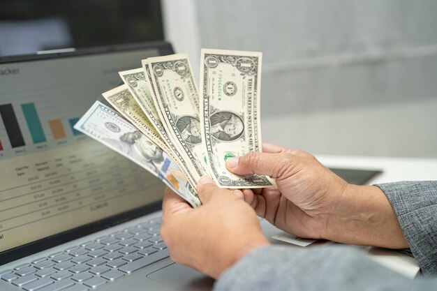 Photo asian accountant holding us dollar banknotes in office