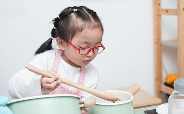 Asian adorable little girl cooking at kitchen