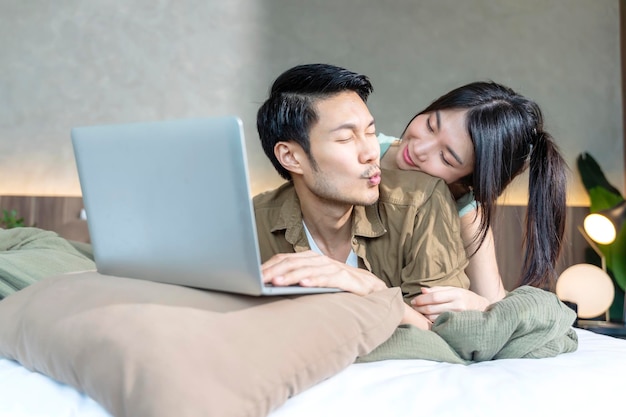 Asian adult lover marry couple enjoy watching horror online movie from laptop or tablet in blanket on bed at homehome quarantine isolation lifetyle