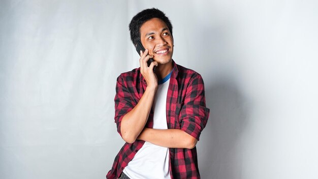 Photo asian adult man wearing red flannel calling someone and get idea with smiling face isolated white background