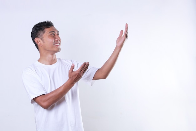 An Asian adult man wearing a white tshirt looks on and opens his arms to the side with copy space